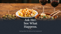 An image with three food plates on a wooden table: a plate of fries with cheese sauce, a bowl of olives, and a bowl of salad, alongside two glasses of red wine. Large white text reads 'Ask Her.